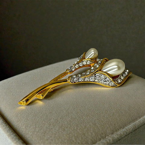 Vintage Edith Vanderbilt gold‑tone arum flowers brooch featuring two sculptural blooms with faux pearls and clear pave rhinestones, shown in various styled settings to highlight its elegant curves and luminous detail.