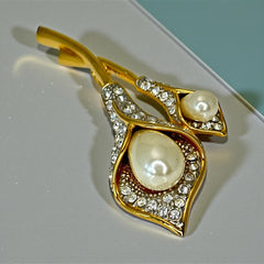 Vintage Edith Vanderbilt gold‑tone arum flowers brooch featuring two sculptural blooms with faux pearls and clear pave rhinestones, shown in various styled settings to highlight its elegant curves and luminous detail.