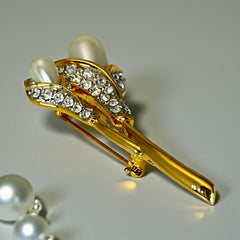 Vintage Edith Vanderbilt gold‑tone arum flowers brooch featuring two sculptural blooms with faux pearls and clear pave rhinestones, shown in various styled settings to highlight its elegant curves and luminous detail.