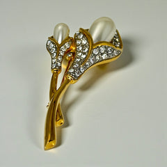 Vintage Edith Vanderbilt gold‑tone arum flowers brooch featuring two sculptural blooms with faux pearls and clear pave rhinestones, shown in various styled settings to highlight its elegant curves and luminous detail.