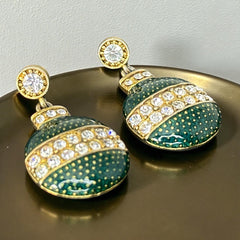 Vintage Eisenberg Ice Christmas ornament earrings with green enamel, clear rhinestone band, and gold-tone stud; signed and festive dangle design.