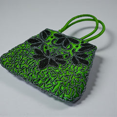 Vintage 1990s emerald green satin evening bag with handsewn black and hematite glass bead floral motifs, dual green handles, and optional crossbody cord, photographed to show craftsmanship, texture, and convertible styling.
