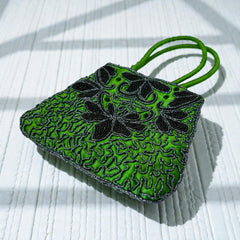 Vintage 1990s emerald green satin evening bag with handsewn black and hematite glass bead floral motifs, dual green handles, and optional crossbody cord, photographed to show craftsmanship, texture, and convertible styling.