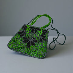 Vintage 1990s emerald green satin evening bag with handsewn black and hematite glass bead floral motifs, dual green handles, and optional crossbody cord, photographed to show craftsmanship, texture, and convertible styling.