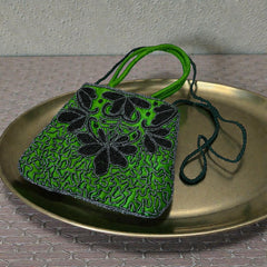 Vintage 1990s emerald green satin evening bag with handsewn black and hematite glass bead floral motifs, dual green handles, and optional crossbody cord, photographed to show craftsmanship, texture, and convertible styling.