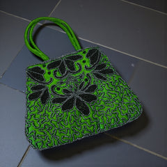 Vintage 1990s emerald green satin evening bag with handsewn black and hematite glass bead floral motifs, dual green handles, and optional crossbody cord, photographed to show craftsmanship, texture, and convertible styling.