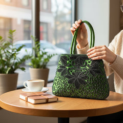 Vintage 1990s emerald green satin evening bag with handsewn black and hematite glass bead floral motifs, dual green handles, and optional crossbody cord, photographed to show craftsmanship, texture, and convertible styling.