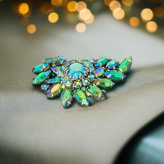 Vintage 1950s brooch featuring layered AB emerald rhinestones in marquise and chaton cuts, set in silver tone metal with a central dog tooth prong setting; photographed to highlight sparkle, craftsmanship, and mid-century design.