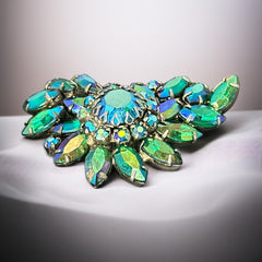 Vintage 1950s brooch featuring layered AB emerald rhinestones in marquise and chaton cuts, set in silver tone metal with a central dog tooth prong setting; photographed to highlight sparkle, craftsmanship, and mid-century design.