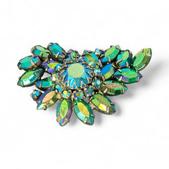Vintage 1950s brooch featuring layered AB emerald rhinestones in marquise and chaton cuts, set in silver tone metal with a central dog tooth prong setting; photographed to highlight sparkle, craftsmanship, and mid-century design.