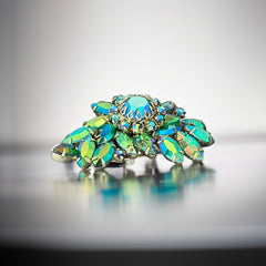 Vintage 1950s brooch featuring layered AB emerald rhinestones in marquise and chaton cuts, set in silver tone metal with a central dog tooth prong setting; photographed to highlight sparkle, craftsmanship, and mid-century design.