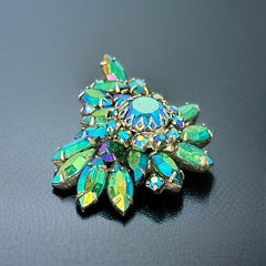 Vintage 1950s brooch featuring layered AB emerald rhinestones in marquise and chaton cuts, set in silver tone metal with a central dog tooth prong setting; photographed to highlight sparkle, craftsmanship, and mid-century design.