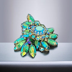 Vintage 1950s brooch featuring layered AB emerald rhinestones in marquise and chaton cuts, set in silver tone metal with a central dog tooth prong setting; photographed to highlight sparkle, craftsmanship, and mid-century design.