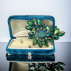 Vintage 1950s brooch featuring layered AB emerald rhinestones in marquise and chaton cuts, set in silver tone metal with a central dog tooth prong setting; photographed to highlight sparkle, craftsmanship, and mid-century design.