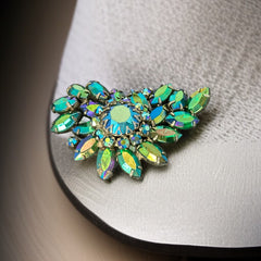Vintage 1950s brooch featuring layered AB emerald rhinestones in marquise and chaton cuts, set in silver tone metal with a central dog tooth prong setting; photographed to highlight sparkle, craftsmanship, and mid-century design.