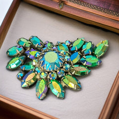 Vintage 1950s brooch featuring layered AB emerald rhinestones in marquise and chaton cuts, set in silver tone metal with a central dog tooth prong setting; photographed to highlight sparkle, craftsmanship, and mid-century design.