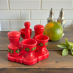 Vintage Emsa West Germany red plastic kitchen set with green flower pattern, featuring salt and pepper shakers, egg cups, and tray.