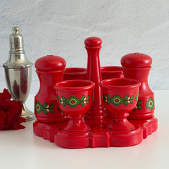 Vintage Emsa West Germany red plastic kitchen set with green flower pattern, featuring salt and pepper shakers, egg cups, and tray.