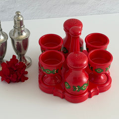 Vintage Emsa West Germany red plastic kitchen set with green flower pattern, featuring salt and pepper shakers, egg cups, and tray.