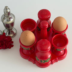 Vintage Emsa West Germany red plastic kitchen set with green flower pattern, featuring salt and pepper shakers, egg cups, and tray.