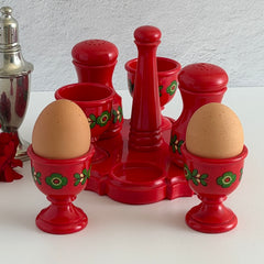 Vintage Emsa West Germany red plastic kitchen set with green flower pattern, featuring salt and pepper shakers, egg cups, and tray.