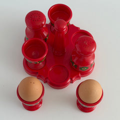 Vintage Emsa West Germany red plastic kitchen set with green flower pattern, featuring salt and pepper shakers, egg cups, and tray.