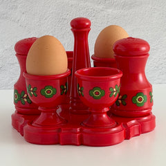 Vintage Emsa West Germany red plastic kitchen set with green flower pattern, featuring salt and pepper shakers, egg cups, and tray.