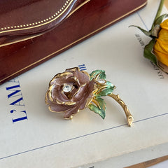 Vintage 1997 Graziano ‘England’s Rose’ brooch with light pink enamel‑painted petals, light green enamel‑painted leaves, clear rhinestones, and a gold‑tone stem, signed on the back.