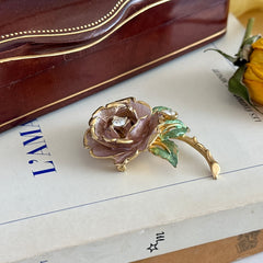 Vintage 1997 Graziano ‘England’s Rose’ brooch with light pink enamel‑painted petals, light green enamel‑painted leaves, clear rhinestones, and a gold‑tone stem, signed on the back.