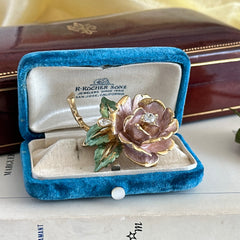 Vintage 1997 Graziano ‘England’s Rose’ brooch with light pink enamel‑painted petals, light green enamel‑painted leaves, clear rhinestones, and a gold‑tone stem, signed on the back.