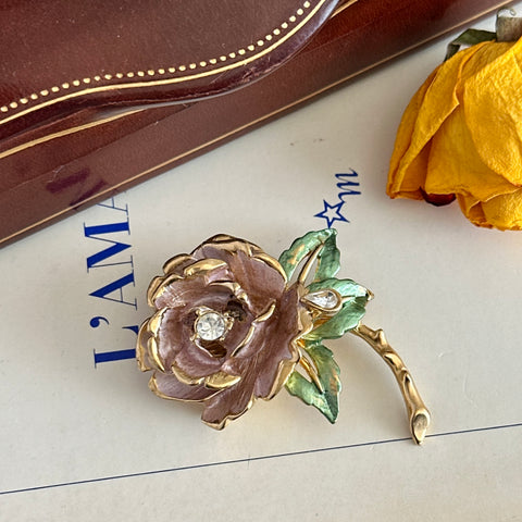 Vintage 1997 Graziano ‘England’s Rose’ brooch with light pink enamel‑painted petals, light green enamel‑painted leaves, clear rhinestones, and a gold‑tone stem, signed on the back.