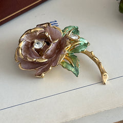 Vintage 1997 Graziano ‘England’s Rose’ brooch with light pink enamel‑painted petals, light green enamel‑painted leaves, clear rhinestones, and a gold‑tone stem, signed on the back.