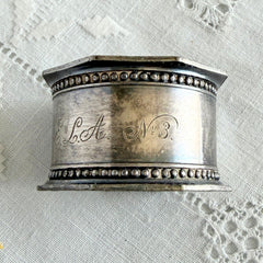 Antique silver‑plated napkin ring with beaded borders and engraved E.L.A. No. 3.