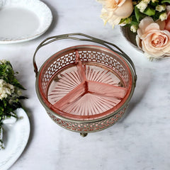 Vintage Farberware relish dish featuring pink Depression glass in a divided three-section design, set in a silver-tone openwork metal basket with arched handle and pedestal base; photographed in soft light to highlight its rosy hue and Art Deco detailing.