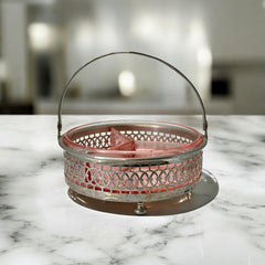 Vintage Farberware relish dish featuring pink Depression glass in a divided three-section design, set in a silver-tone openwork metal basket with arched handle and pedestal base; photographed in soft light to highlight its rosy hue and Art Deco detailing.