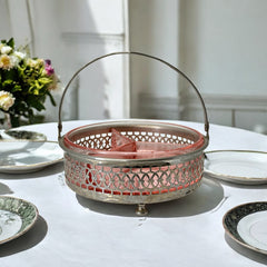 Vintage Farberware relish dish featuring pink Depression glass in a divided three-section design, set in a silver-tone openwork metal basket with arched handle and pedestal base; photographed in soft light to highlight its rosy hue and Art Deco detailing.