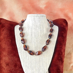 1950s vintage faux amber necklace featuring cognac-colored twisted plastic beads with gold-tone accents and a matching barrel clasp. A shiny, elegant piece in very good vintage condition, perfect for sustainable and eco-conscious fashion.