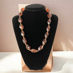 1950s vintage faux amber necklace featuring cognac-colored twisted plastic beads with gold-tone accents and a matching barrel clasp. A shiny, elegant piece in very good vintage condition, perfect for sustainable and eco-conscious fashion.