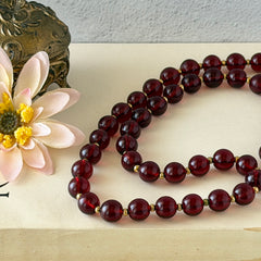 Vintage cherry amber acrylic bead necklace with gold tone spacers and clasp displayed on neutral background.