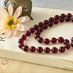 Vintage cherry amber acrylic bead necklace with gold tone spacers and clasp displayed on neutral background.