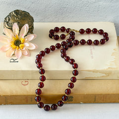 Vintage cherry amber acrylic bead necklace with gold tone spacers and clasp displayed on neutral background.