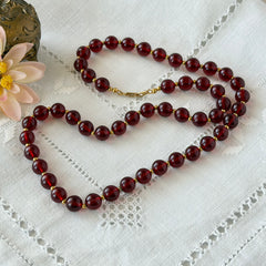 Vintage cherry amber acrylic bead necklace with gold tone spacers and clasp displayed on neutral background.