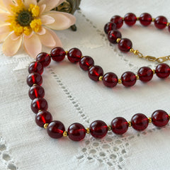 Vintage cherry amber acrylic bead necklace with gold tone spacers and clasp displayed on neutral background.