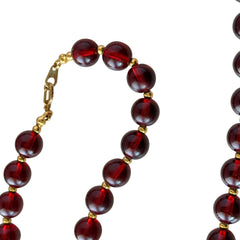 Vintage cherry amber acrylic bead necklace with gold tone spacers and clasp displayed on neutral background.