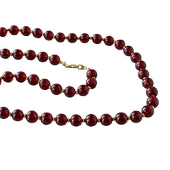 Vintage cherry amber acrylic bead necklace with gold tone spacers and clasp displayed on neutral background.