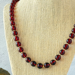 Vintage cherry amber acrylic bead necklace with gold tone spacers and clasp displayed on neutral background.