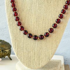 Vintage cherry amber acrylic bead necklace with gold tone spacers and clasp displayed on neutral background.