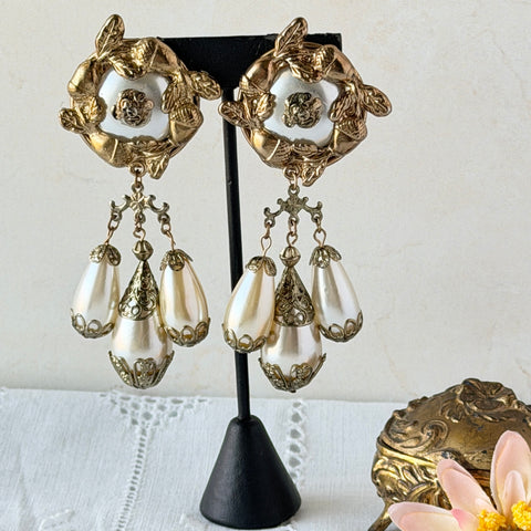 Vintage 1990s gold‑tone acorn design clip‑on earrings with faux pearl dangles, shown from front and back on original card.