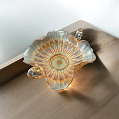 Vintage Fenton marigold carnival glass dish with stippled rays pattern, featuring a ruffled scalloped edge and clear double handles; warm amber iridescence with visible air bubbles 