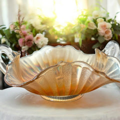 Vintage Fenton marigold carnival glass dish with stippled rays pattern, featuring a ruffled scalloped edge and clear double handles; warm amber iridescence with visible air bubbles 